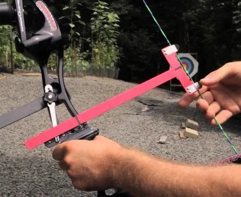 Archery bow sight tool in use outdoors with target in background on gravel range