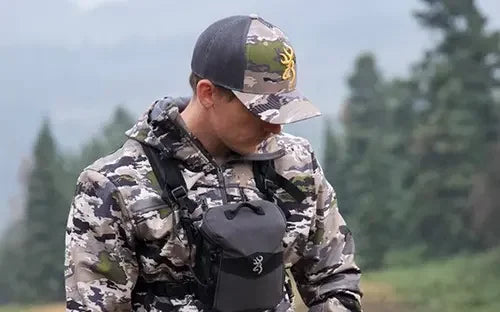 Man wearing camo hunting hat and jacket outdoors in forest setting
