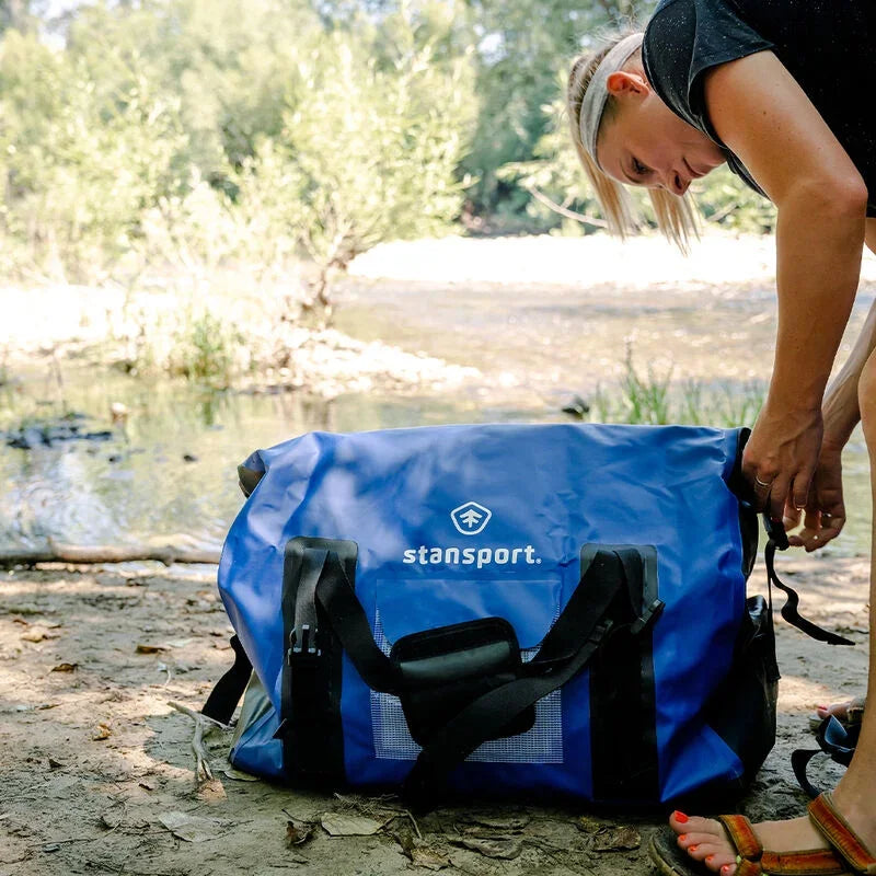Woman by river with blue Stansport waterproof duffel bag outdoors