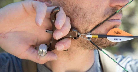Close-up of an archer using a handheld release aid to draw a bow for bowhunting