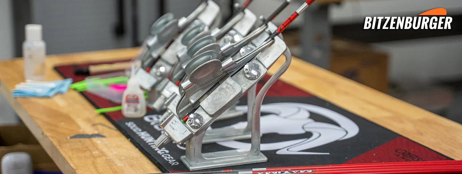 Bitzenburger arrow fletching jigs on workshop table with arrows and BITZENBURGER logo