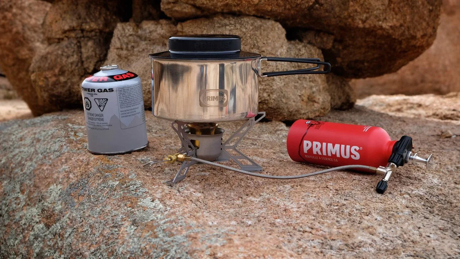 Primus camping stove set with gas and fuel bottle on rocky outdoor surface
