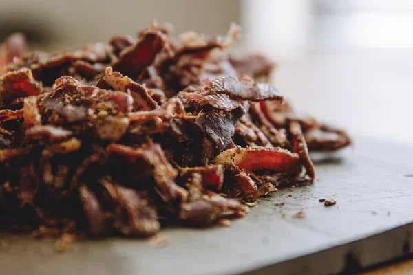 Closeup of homemade beef jerky on a cutting board, ideal for jerky making kits promotion