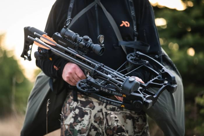 Hunter outdoors holding Mission Sub-1 XR crossbow with scope and arrows