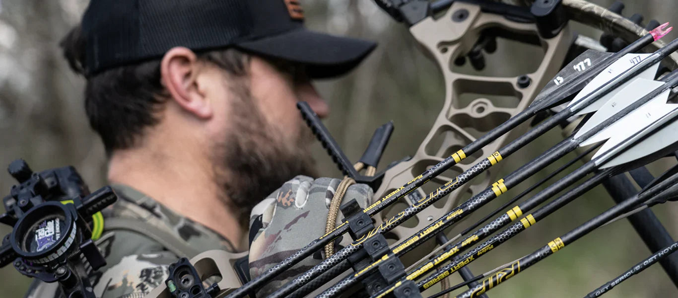 Hunter in camouflage holding compound bow with Victory Archery arrows outdoors