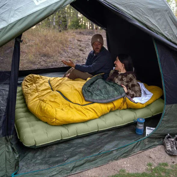 Couple camping in tent with sleeping bags on air mattress, outdoor forest setting