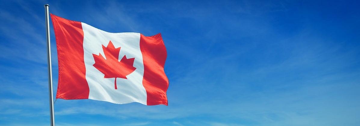 Canadian flag with red maple leaf waving against clear blue sky