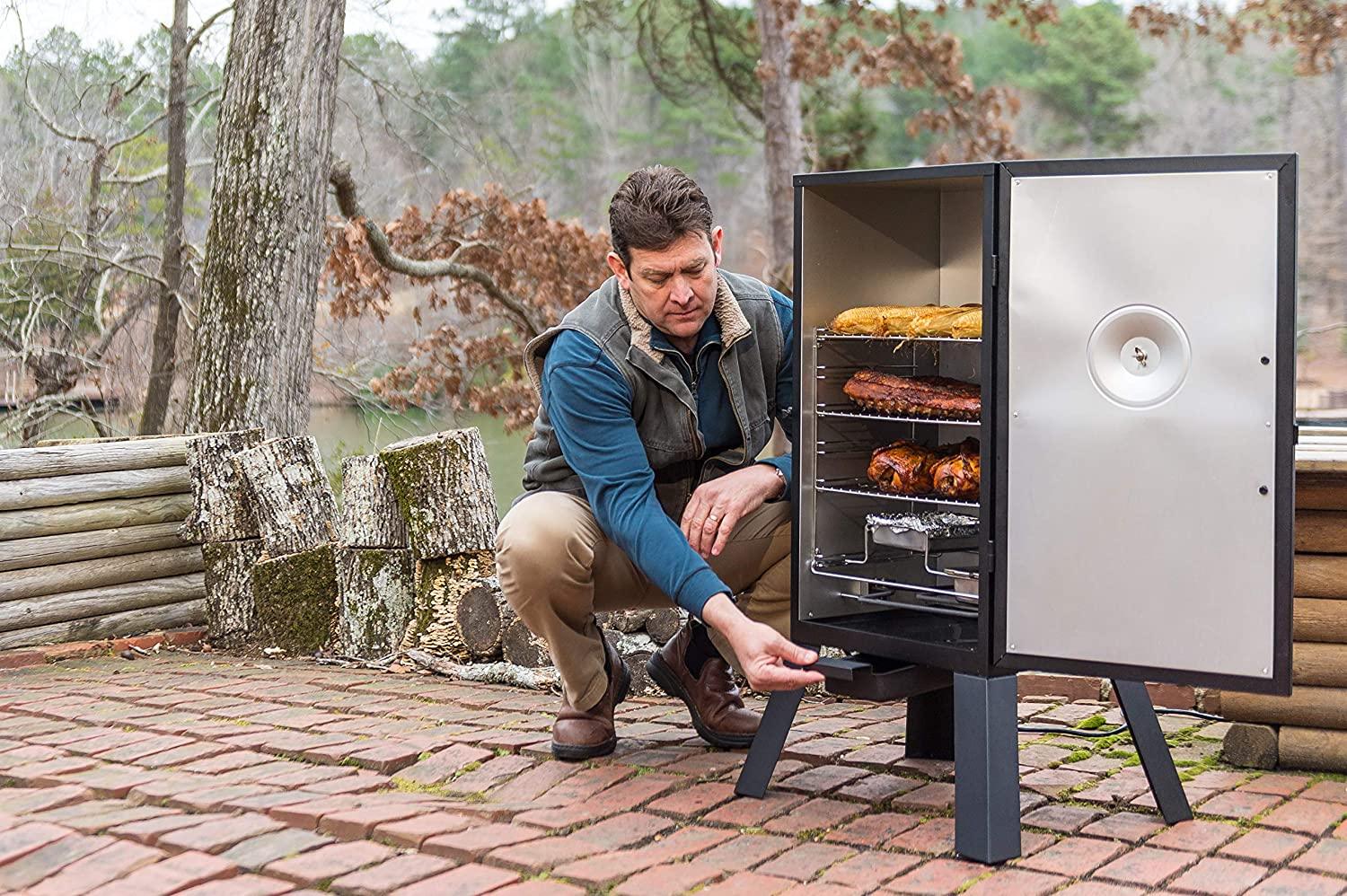 Man using Bradley Smoker outdoor on patio, loaded with smoked meats and bread.