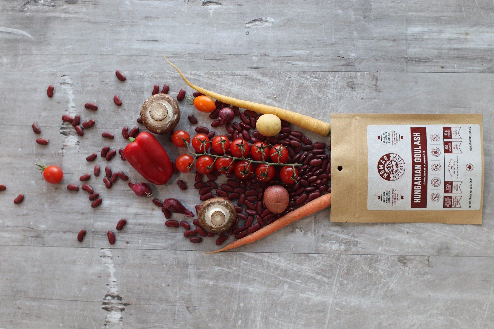 Nomad Nutrition Hungarian Goulash pouch with fresh vegetables and beans on rustic table