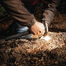 Person using SOG outdoor survival knife to spark fire on forest ground
