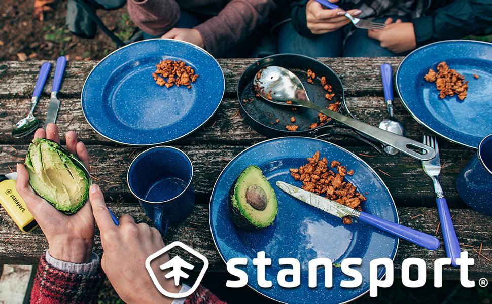 Camping meal outdoors with blue plates, avocado, and Stansport gear on wooden picnic table