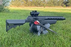Umarex airgun resting on bag in grassy outdoor field with arrows nearby