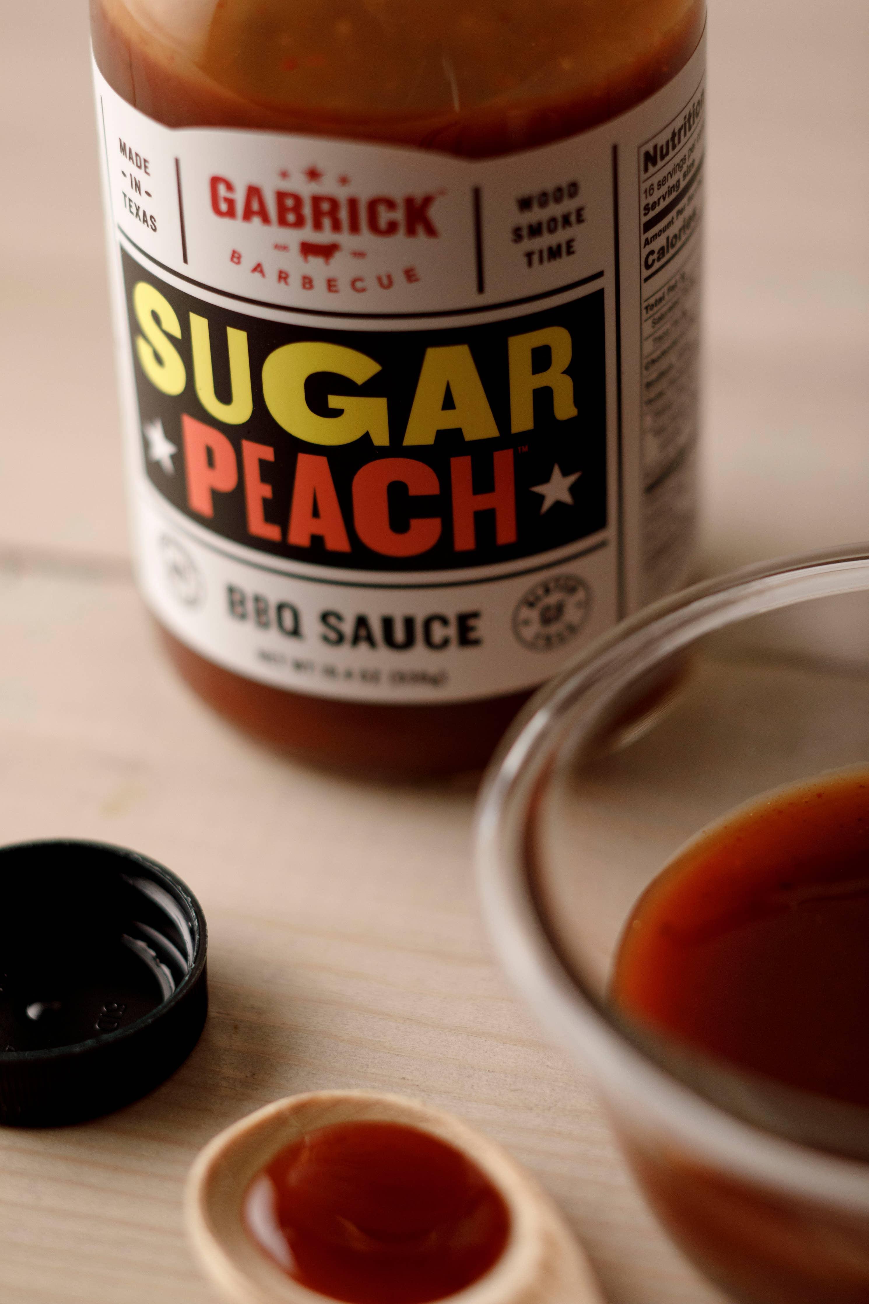 Sugar Peach BBQ sauce bottle with open cap and bowl of barbecue sauce on table
