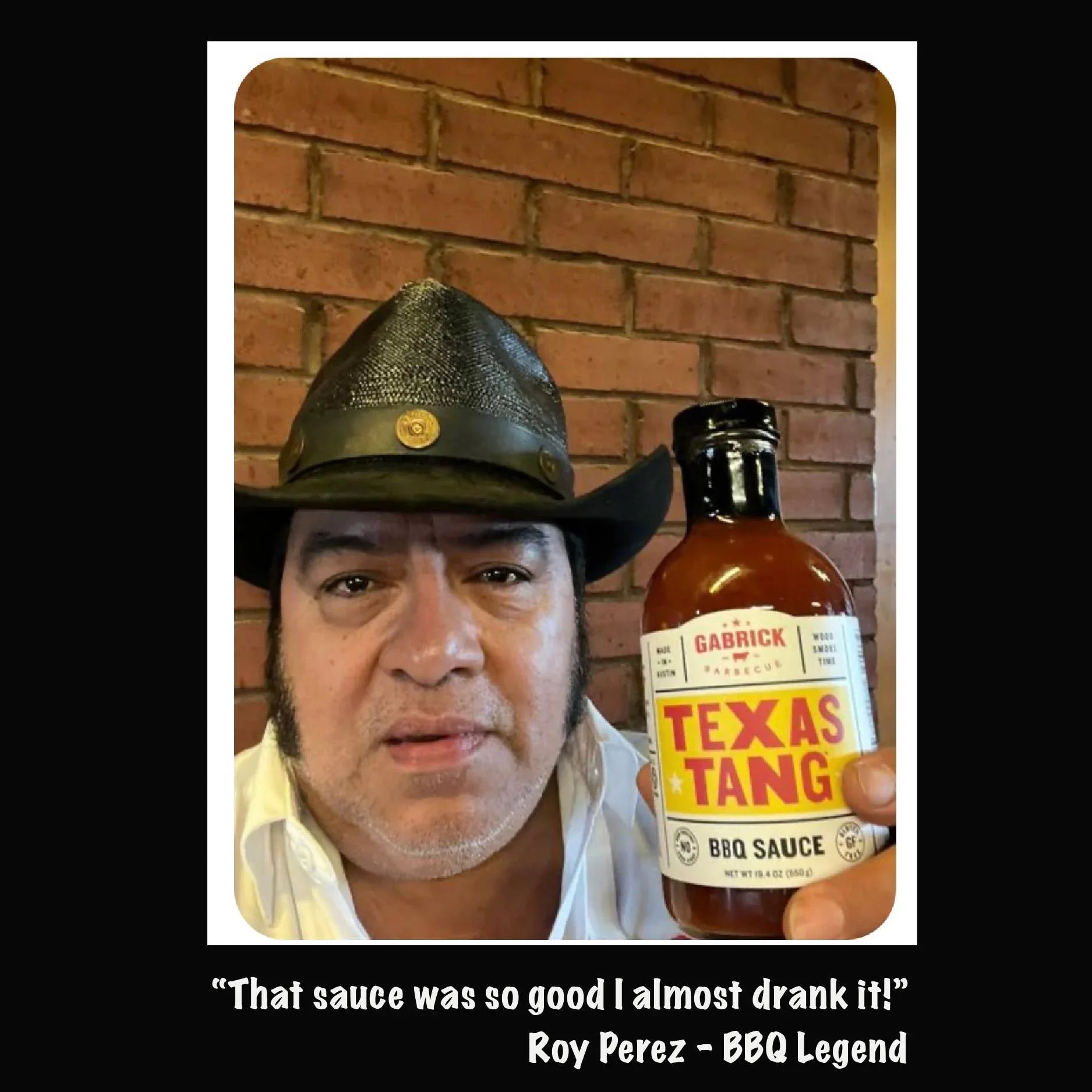 Man in cowboy hat holding Gabrick Texas Tang BBQ sauce bottle against brick wall