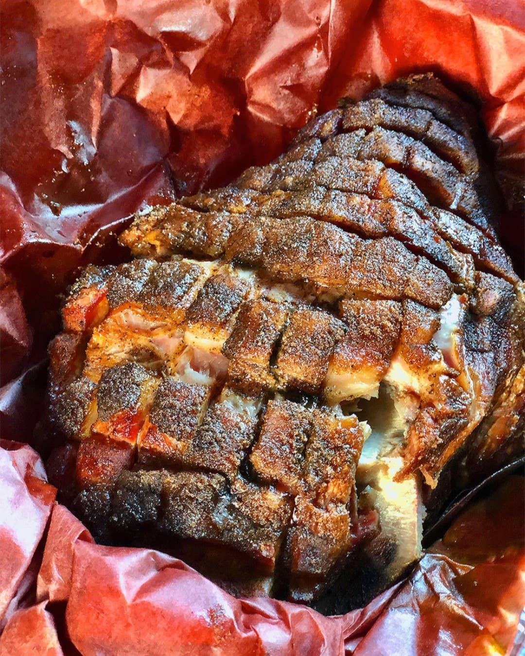 Smoked pork shoulder with crispy bark, sliced on red butcher paper, ideal for outdoor cooking