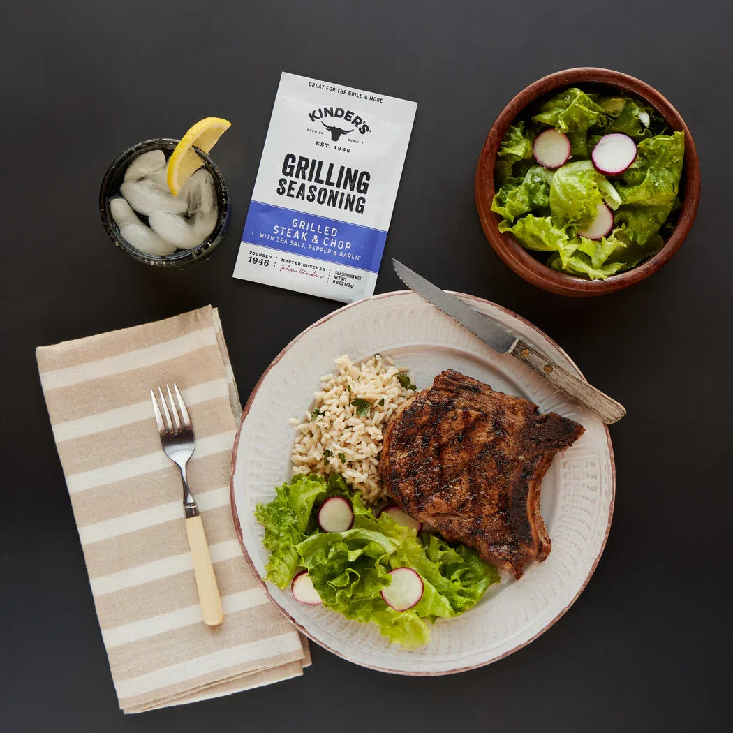 Grilled steak with rice, fresh salad, and grilling seasoning on a table setting