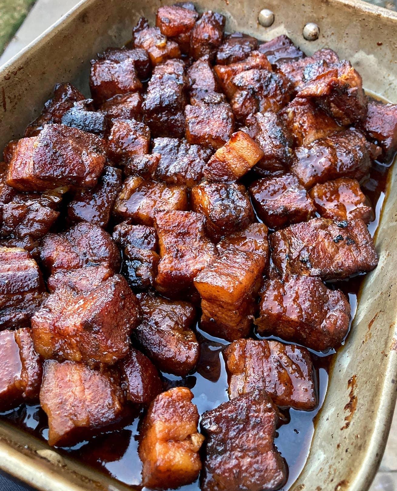 Tray of smoked pork belly burnt ends with caramelized barbecue glaze outdoors