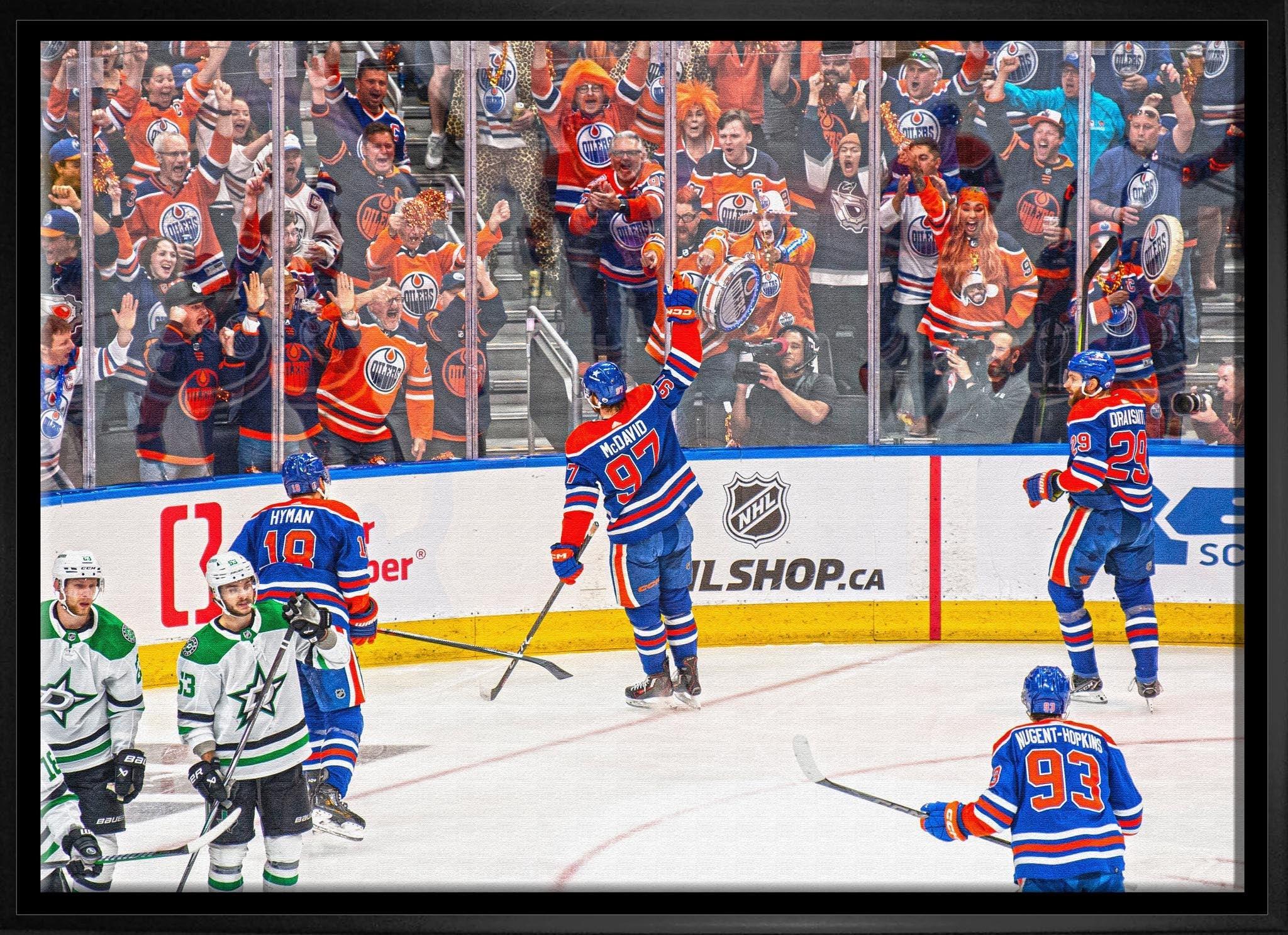 Edmonton Oilers hockey players celebrate a goal on ice with cheering fans in arena stands.