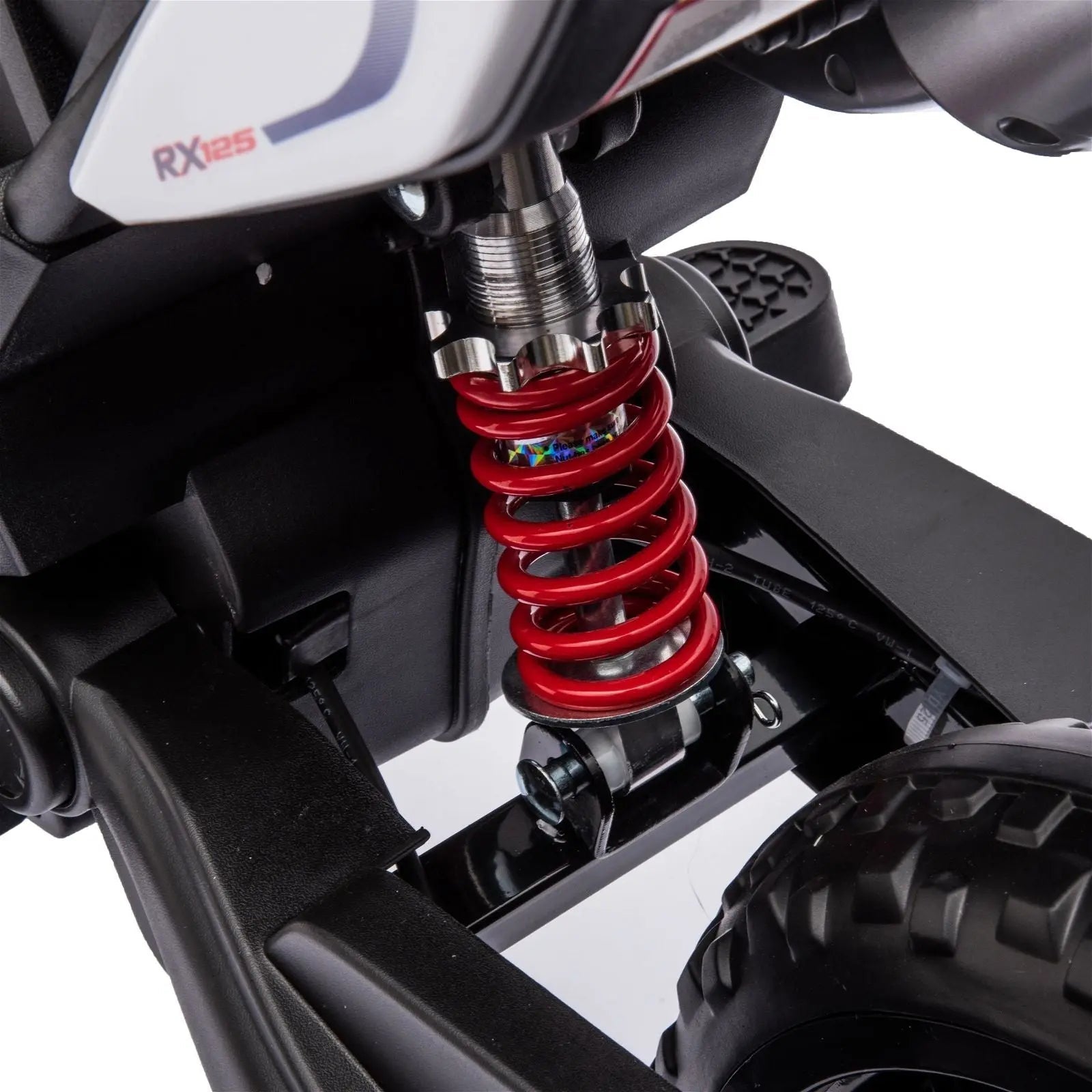 Close-up of red coil rear suspension on kids' ride-on motorcycle with black tire