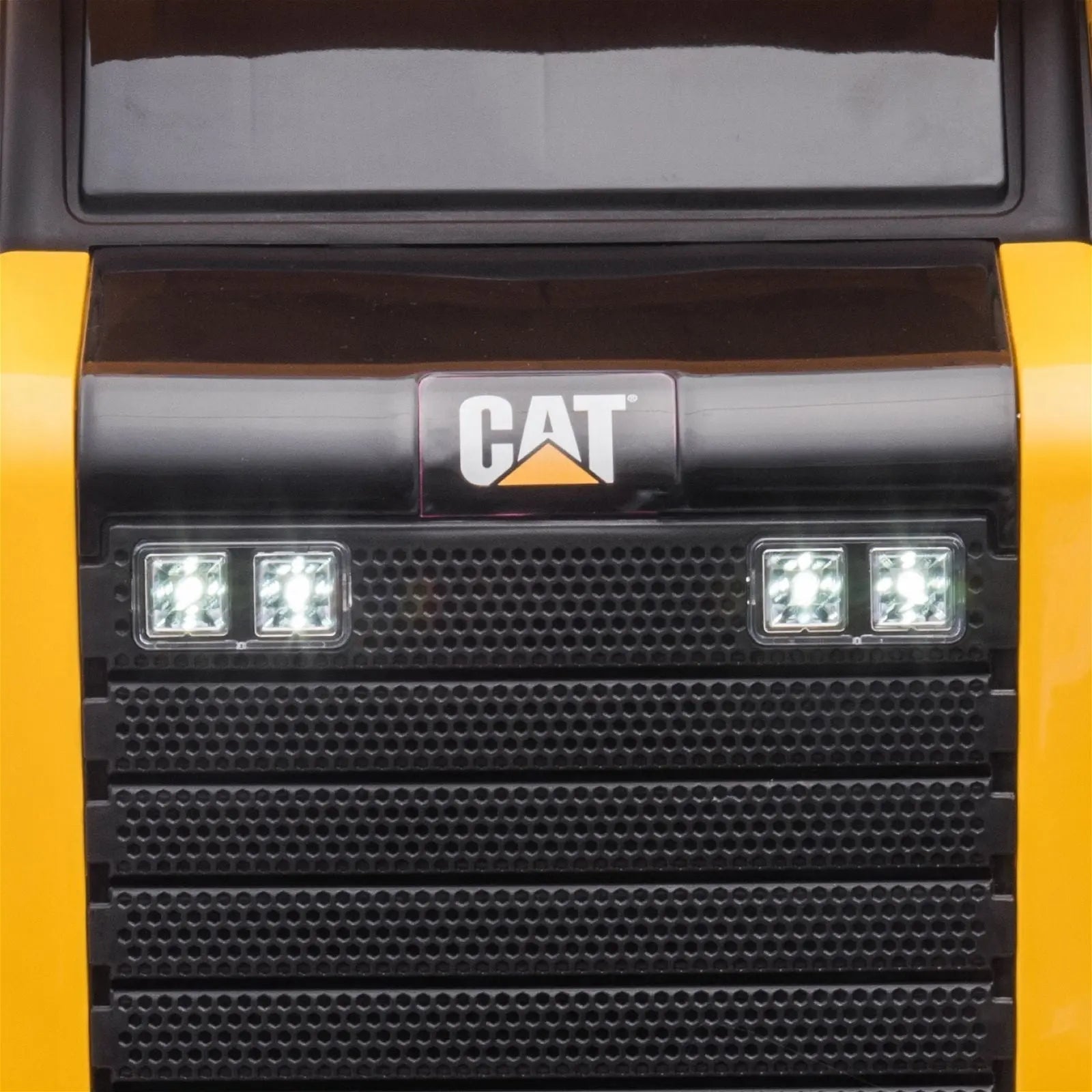 Close-up of yellow CAT ride-on dump truck front grille with headlights and logo
