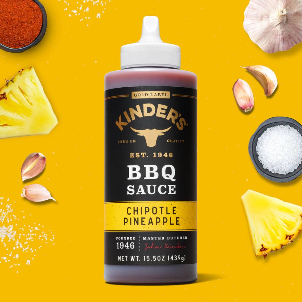 Kinder’s Chipotle Pineapple BBQ sauce bottle with garlic, pineapple, seasoning, and salt on yellow background