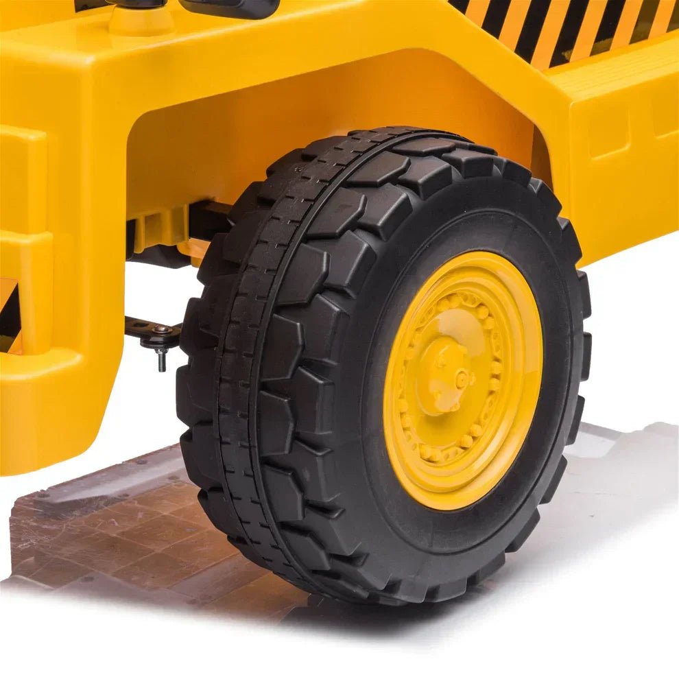 Close-up of large black rubber tire with yellow rim on 12V electric toy dump truck for kids