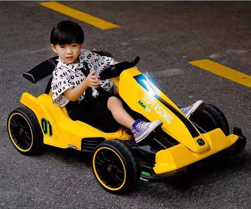 Smiling child driving yellow SUPERSOMIC go-kart on asphalt road with yellow markings