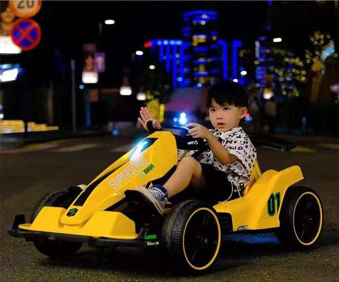 Child driving yellow electric go-kart at night city street, neon lights in background