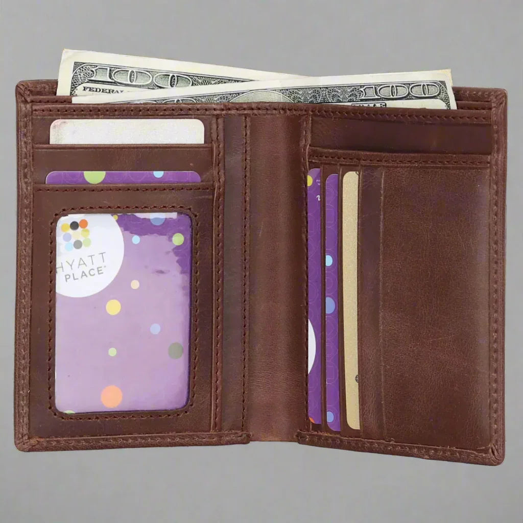 Open brown leather wallet with cash and credit cards inside on gray background.