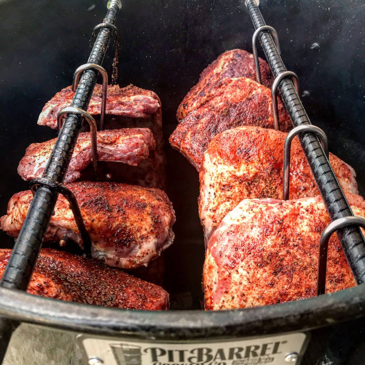 Seasoned pork ribs and meat hanging in a smoker barrel for outdoor cooking