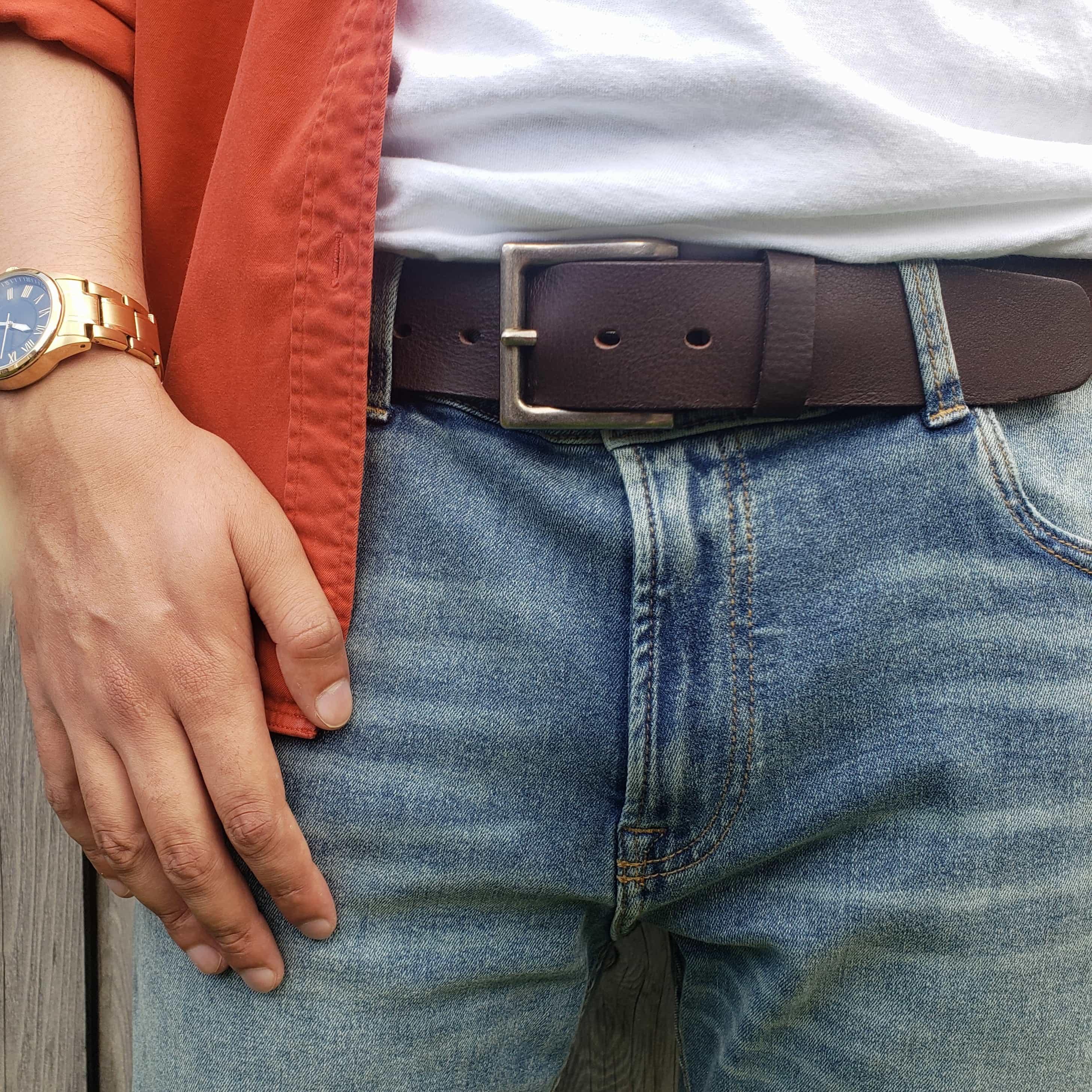 Brown leather belt with metal buckle on blue jeans, casual outdoor clothing