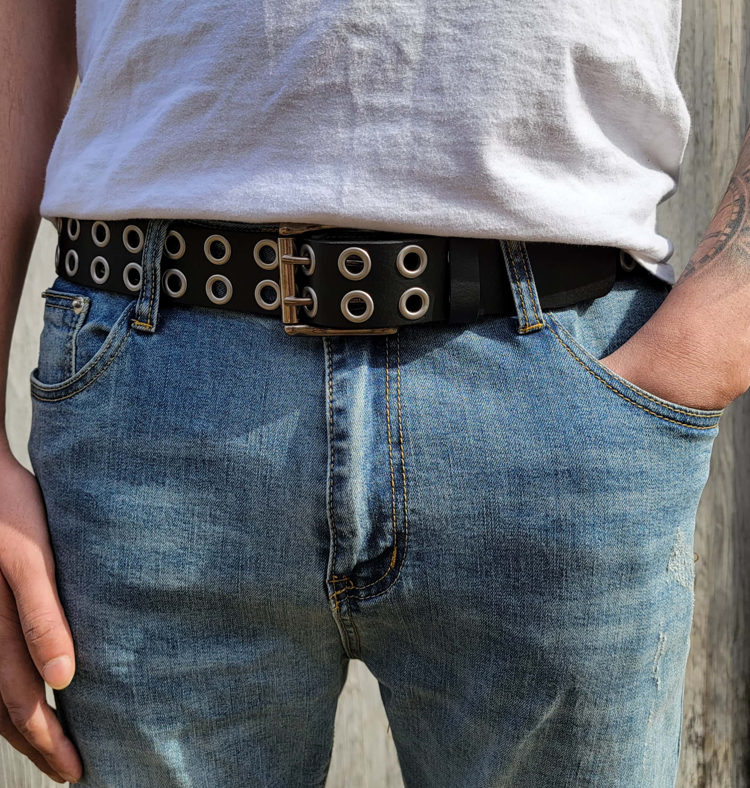 Double grommet black leather belt paired with blue jeans for outdoor wear