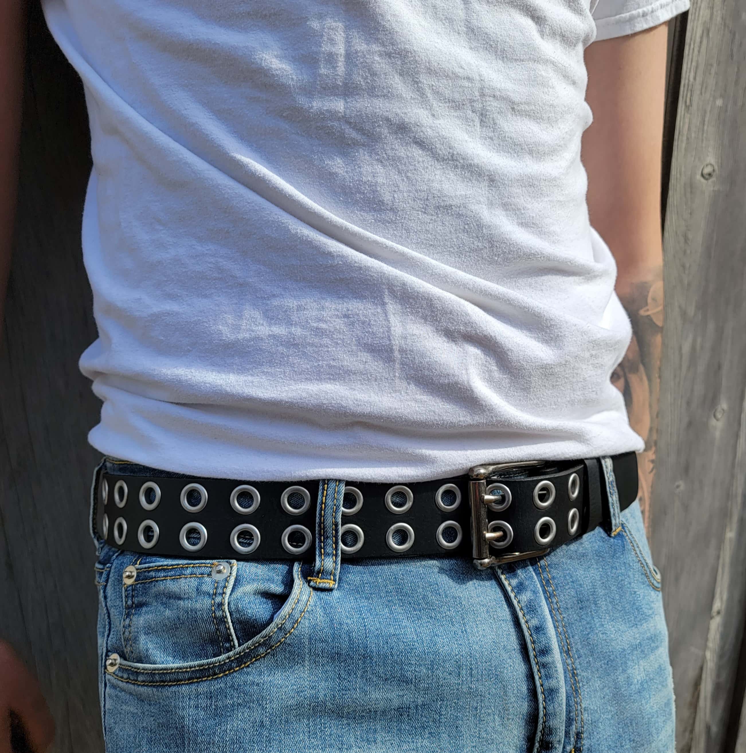 Black grommet belt with silver eyelets worn with blue jeans and white t-shirt outdoors