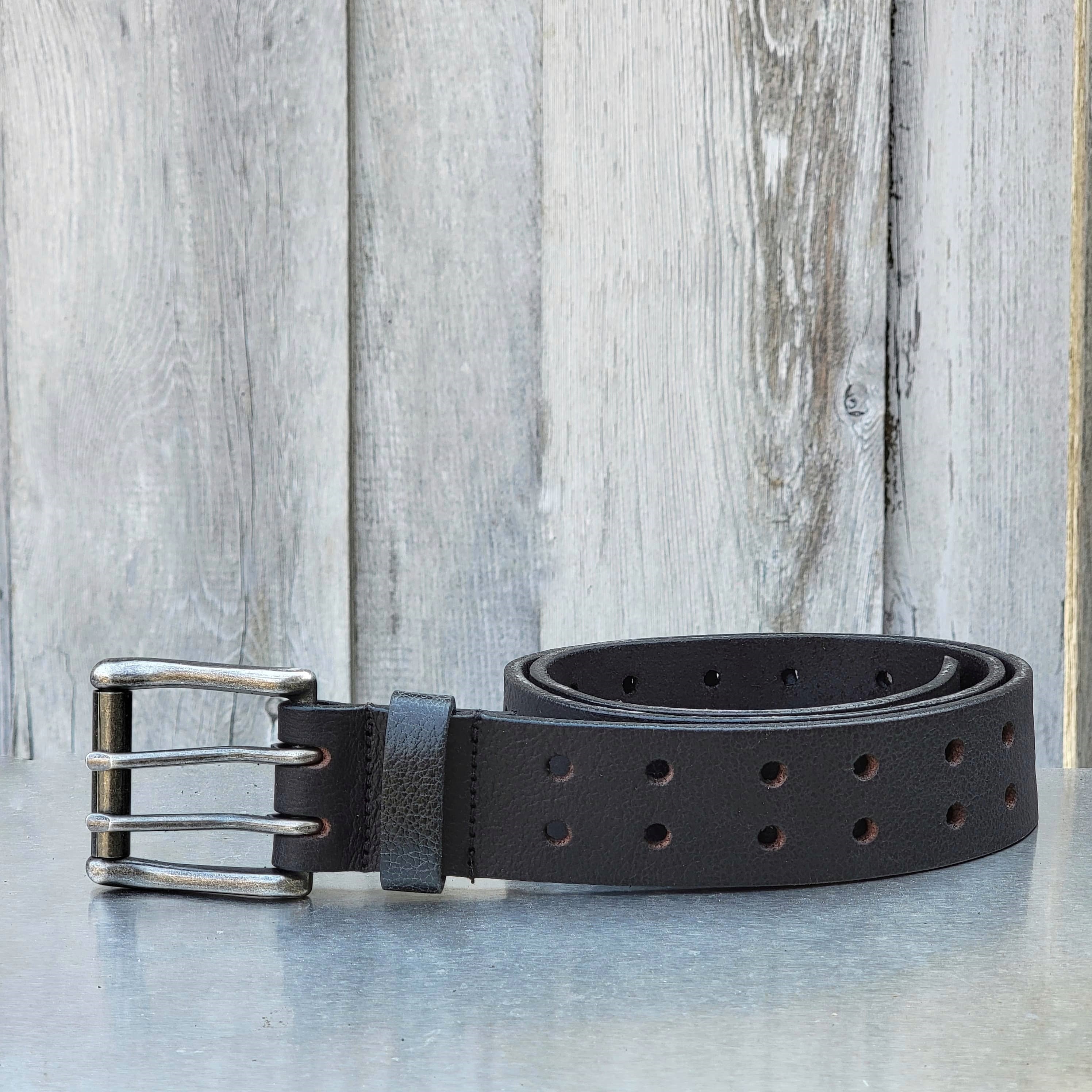 Black leather double prong belt with metal buckle, outdoor wood background
