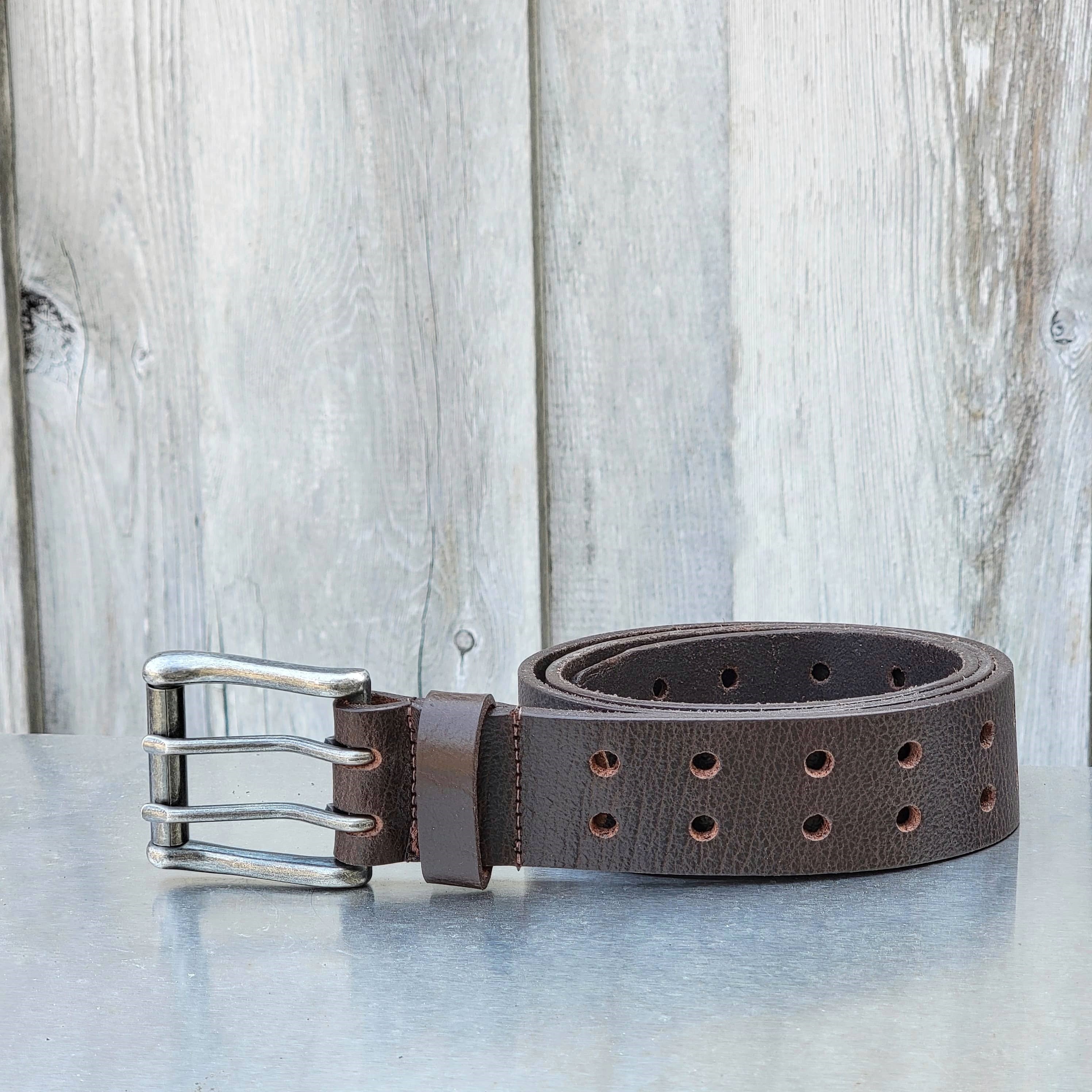 Brown leather belt with metal double prong buckle, outdoor rustic background