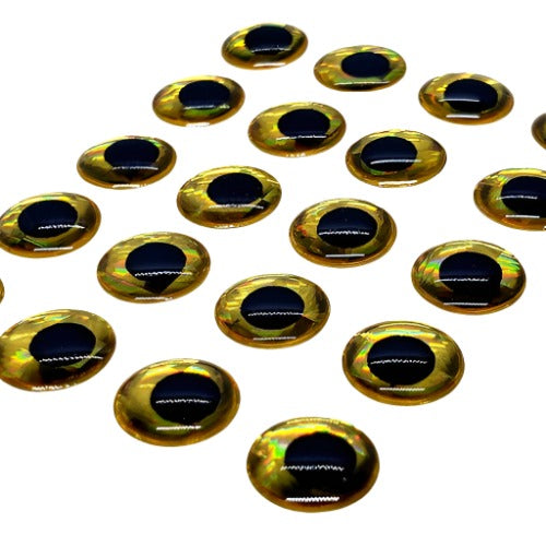 Glossy gold and black adhesive lure eyes for fishing tackle, arranged on a white surface