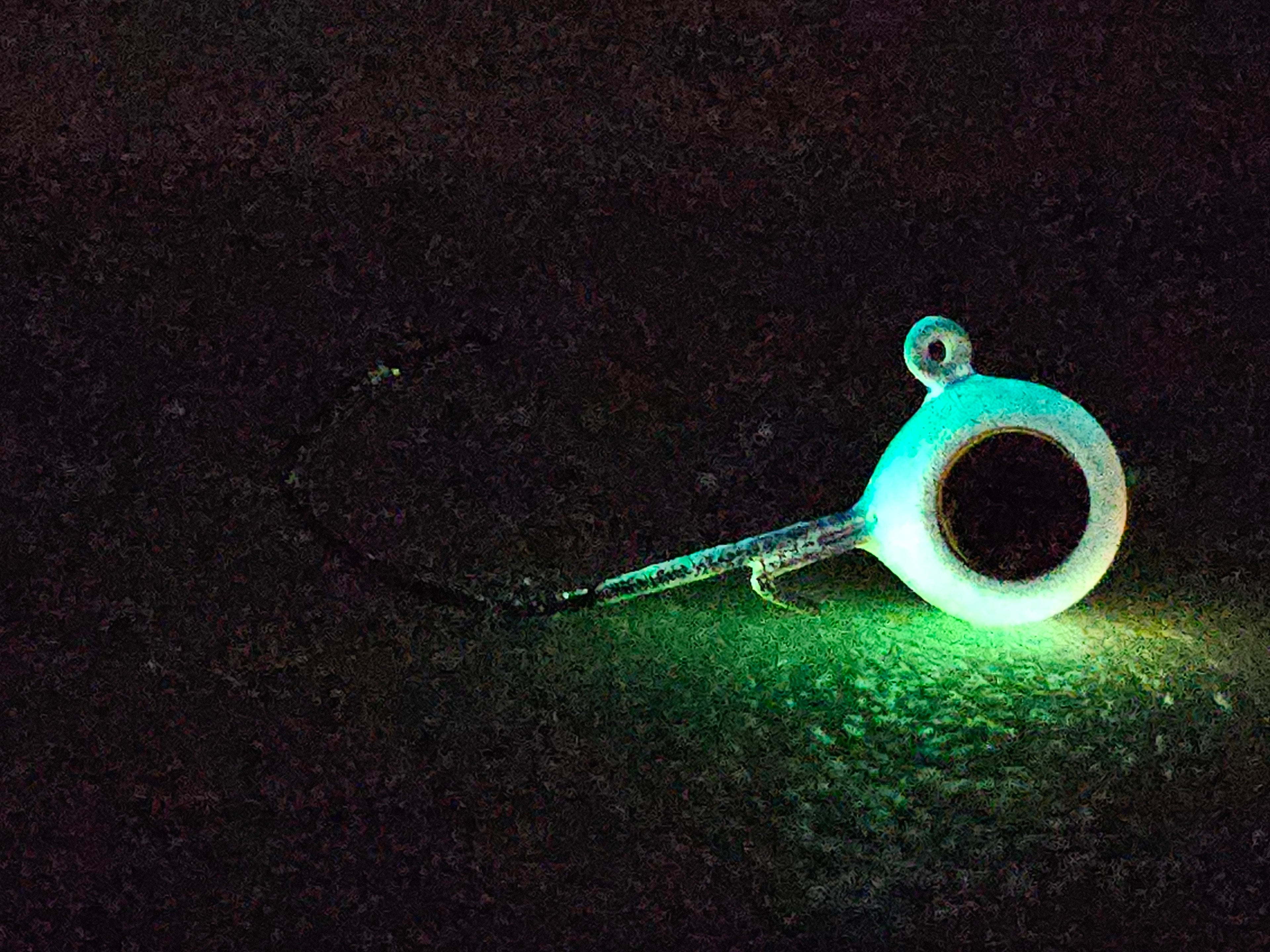 Glow in the dark fishing rod guide illuminated on textured outdoor ground