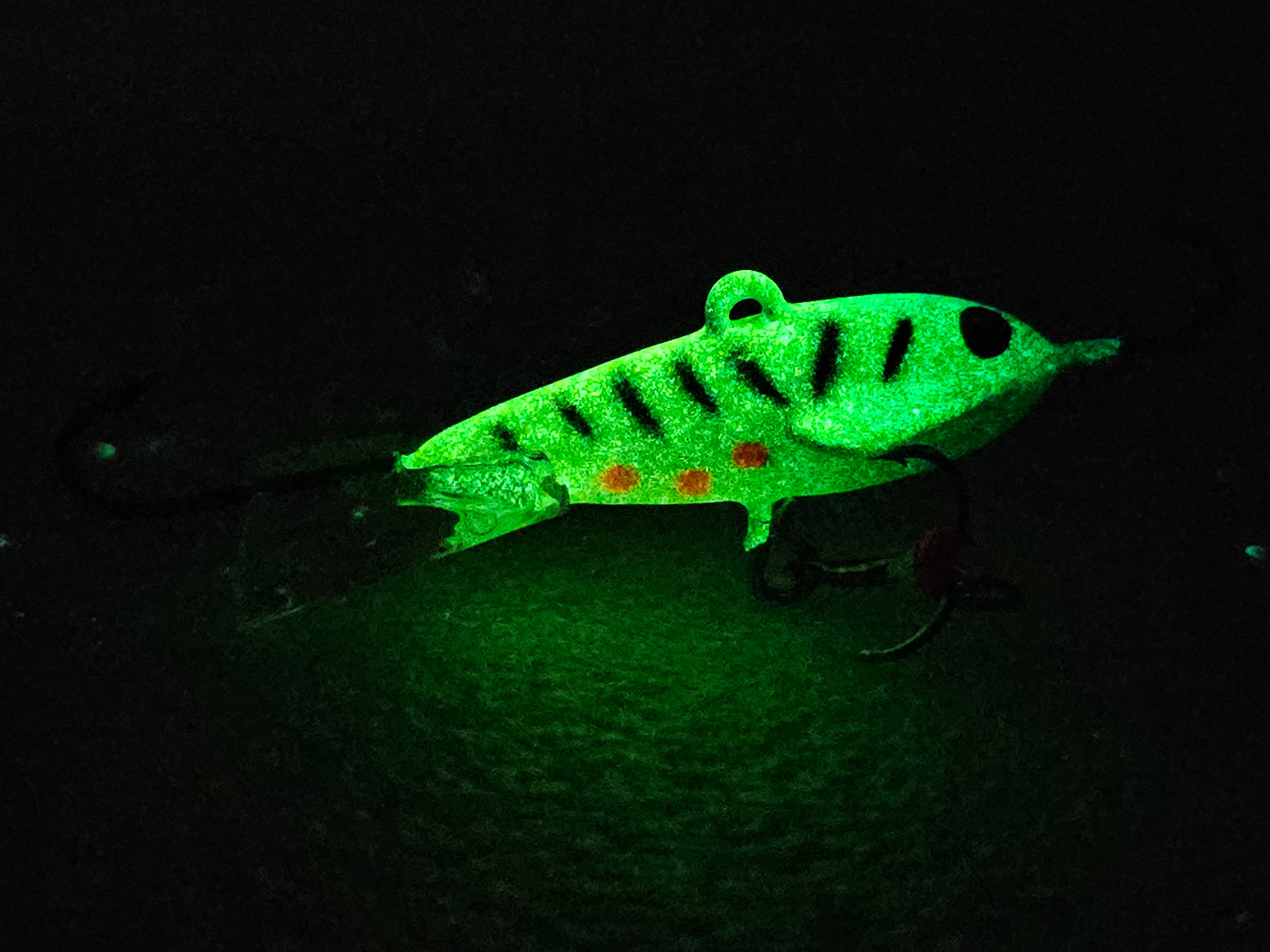Glow in the dark fishing lure with hooks, green and black pattern, night setting
