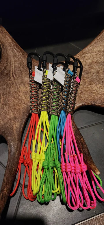 Colorful paracord lanyards with carabiners displayed on antlers, outdoor camping gear.