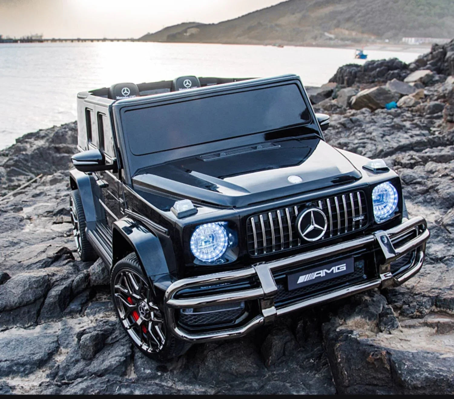 Black Mercedes-Benz AMG toy car SUV with LED headlights on rocky waterfront