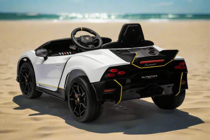 White Lamborghini toy car on sandy beach with ocean in background