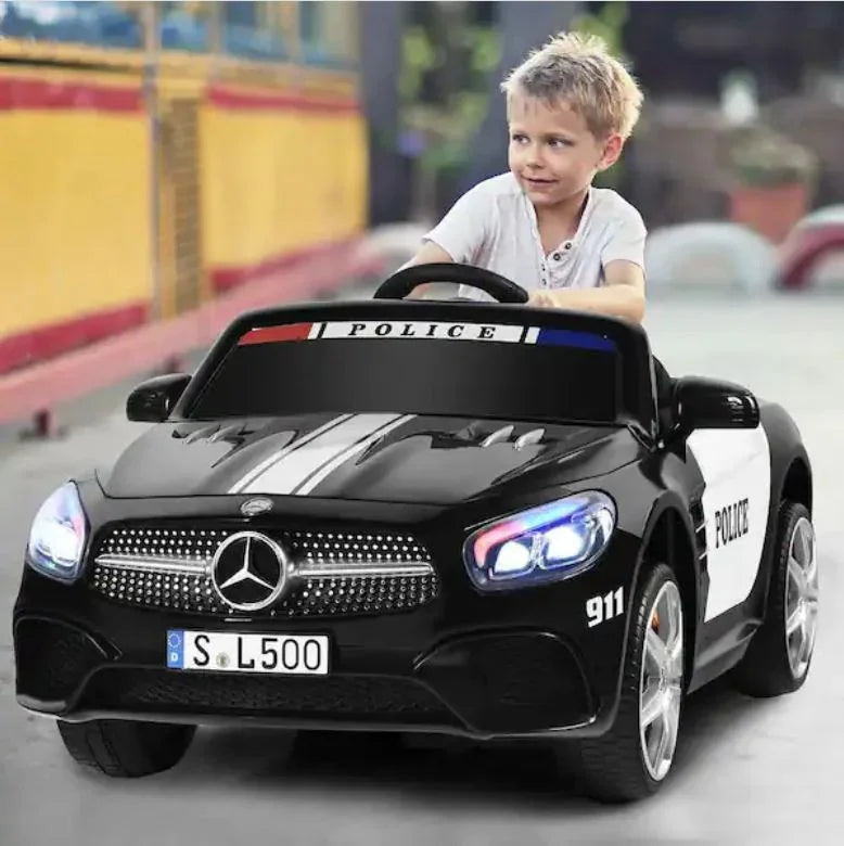 Smiling boy drives black toy police car Mercedes Benz electric ride-on with LED lights outdoors.