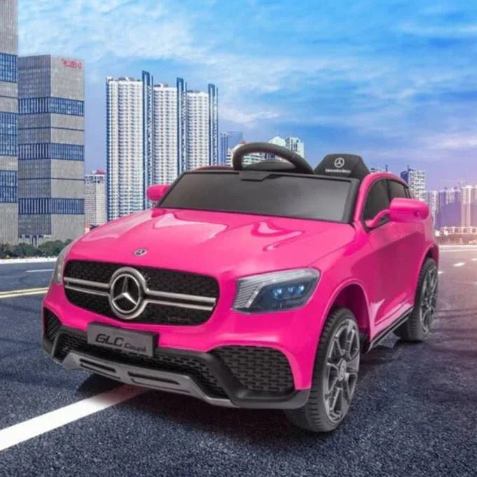 Pink Mercedes toy car GLC Coupe for kids on urban road with tall city buildings
