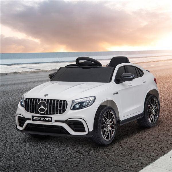 White Mercedes AMG ride-on toy car for kids on an empty road at sunset