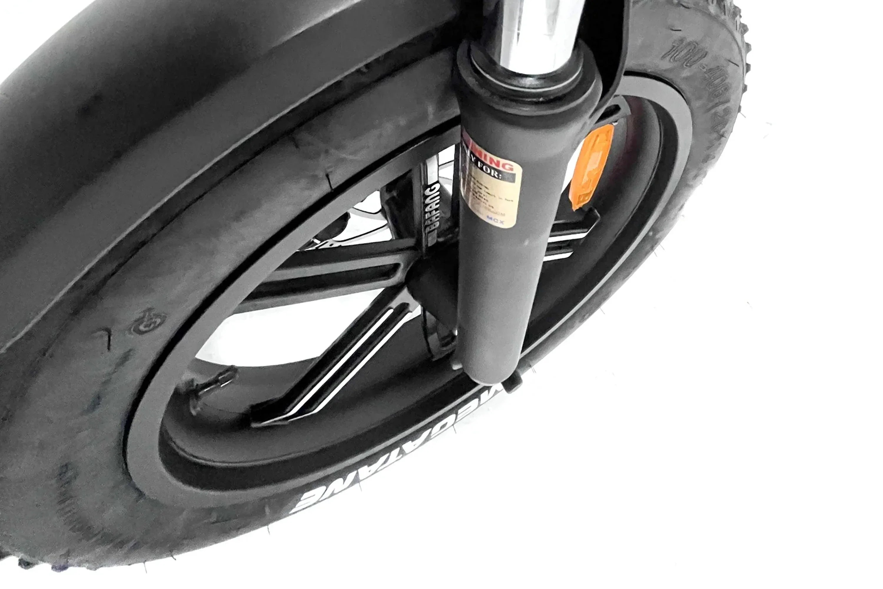 Close-up of urban e-bike front tire, suspension fork, and MEGARAVE wheel on white background.