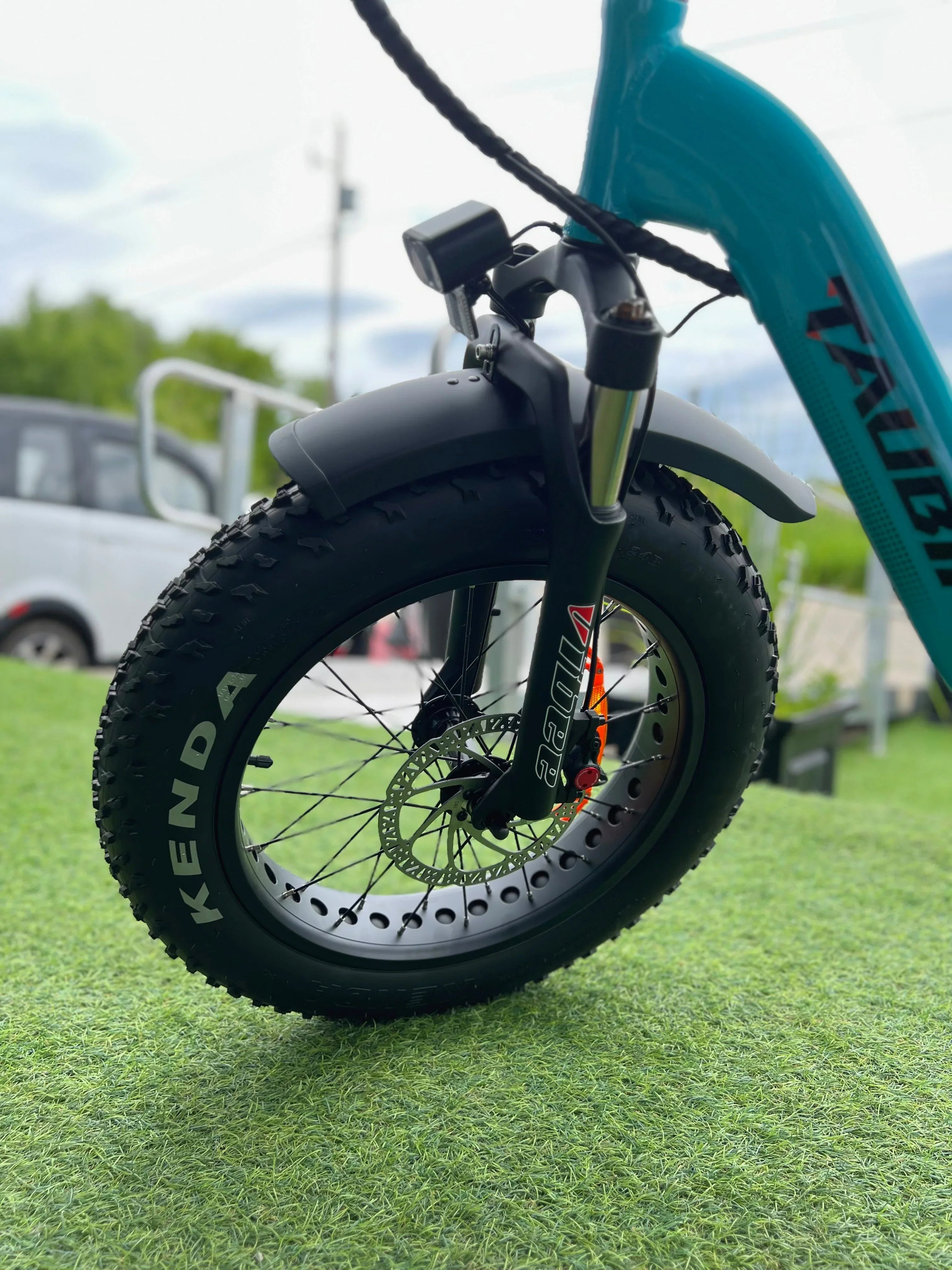 Close-up of a Kenda fat bike front tire with disc brake on grass
