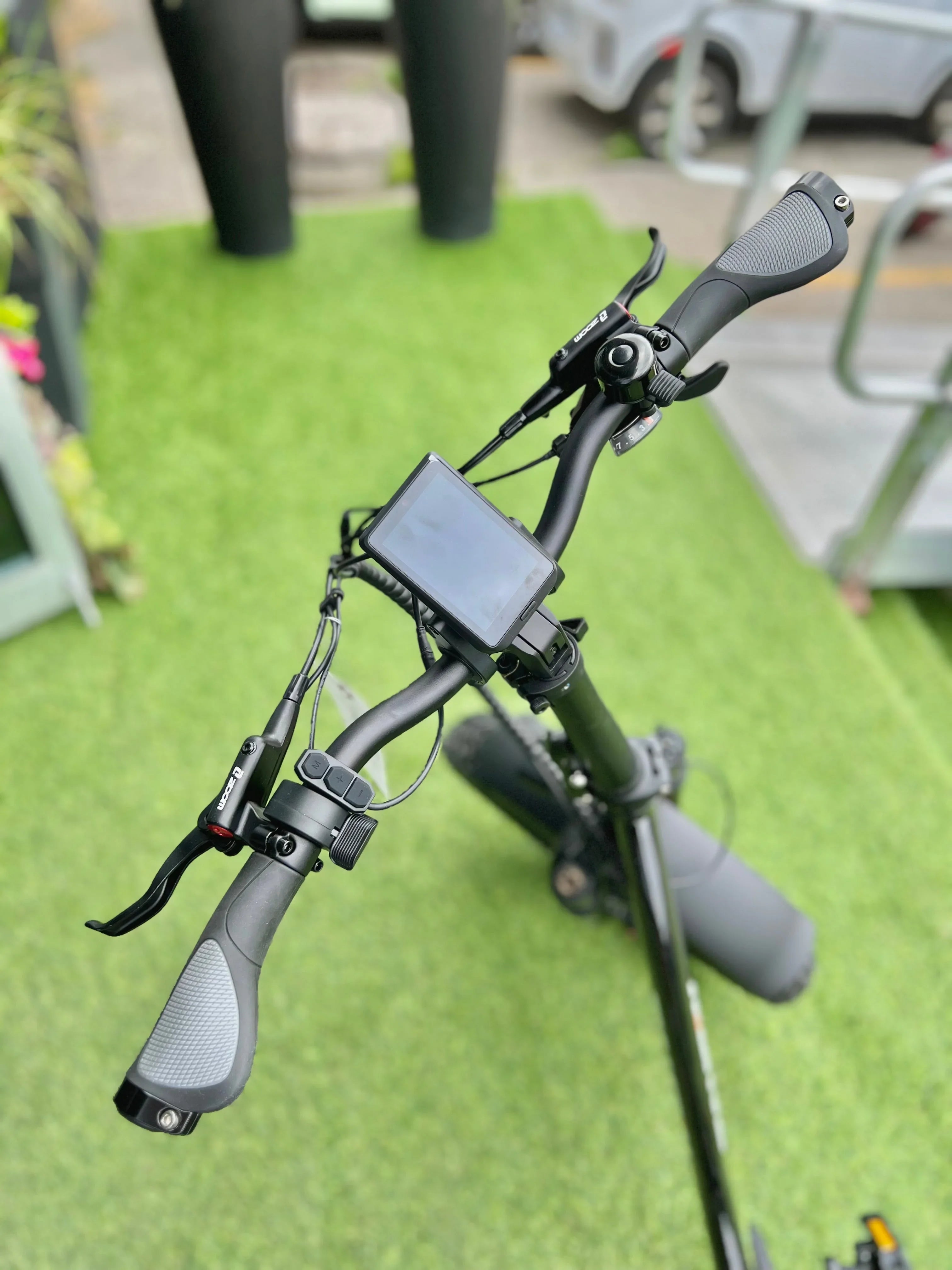 Electric scooter handlebar with display on artificial grass, outdoor setting