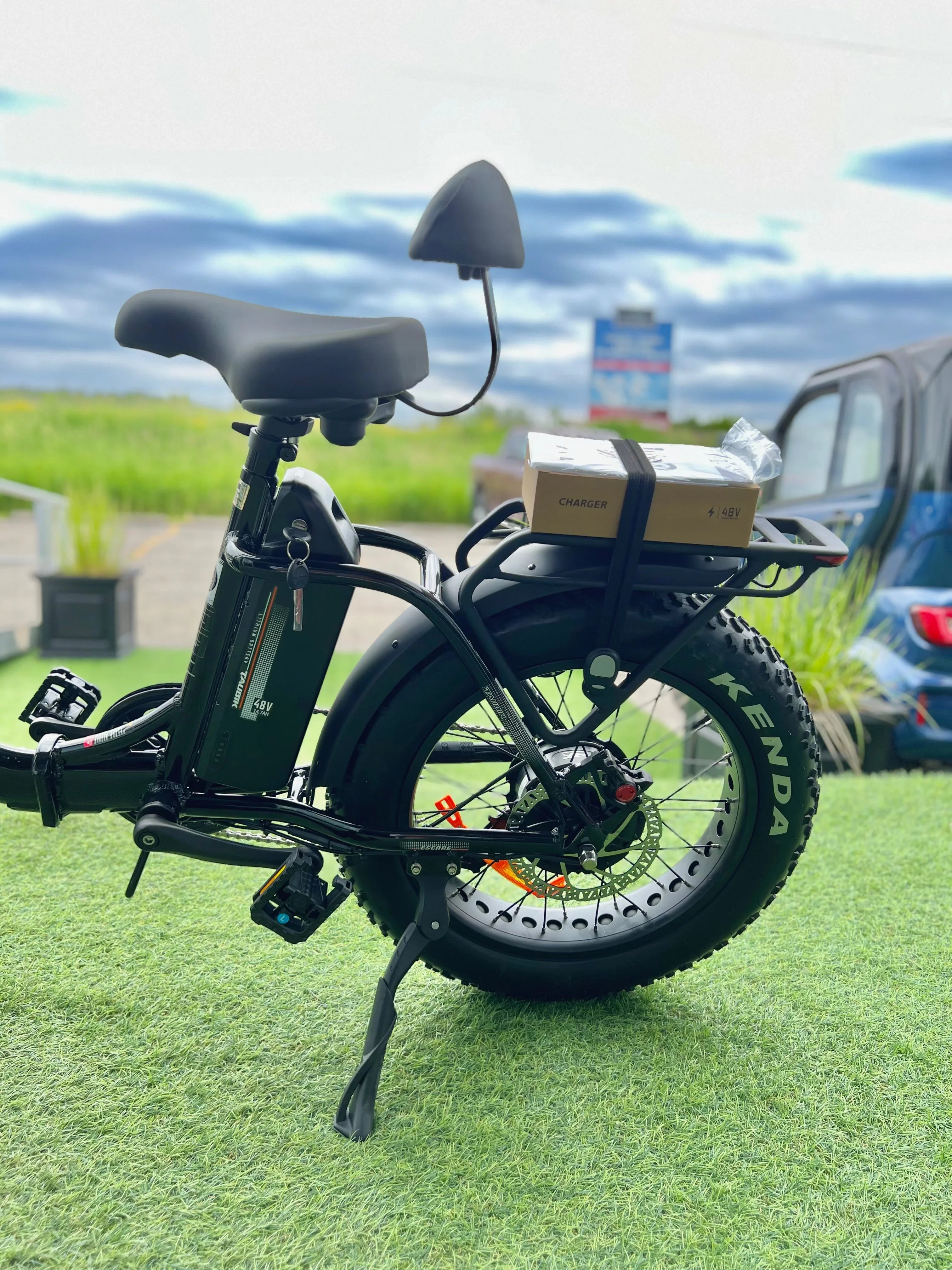 Electric bike with Kenda fat tires, rear rack, and 48V battery on grass outdoors