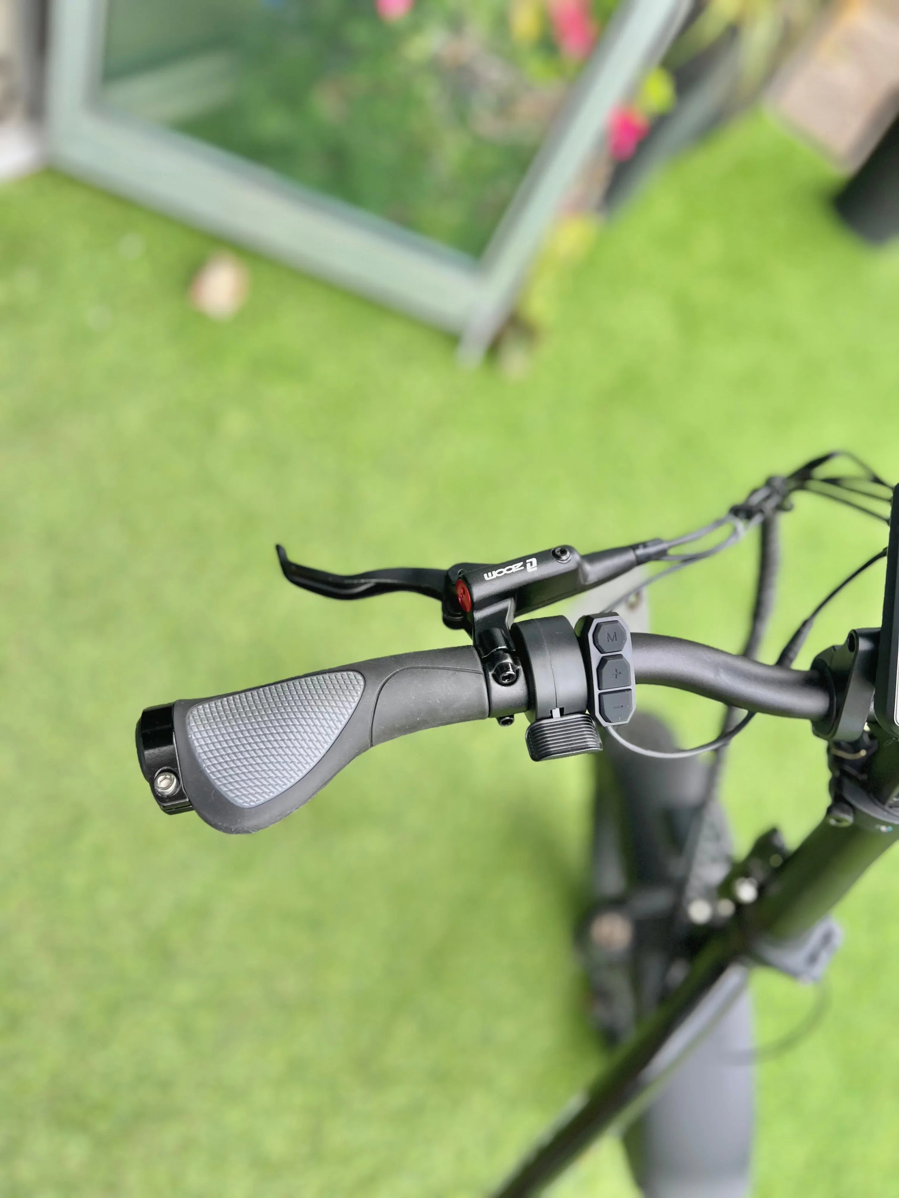 Electric scooter handlebar with ergonomic grip and control buttons on green grass