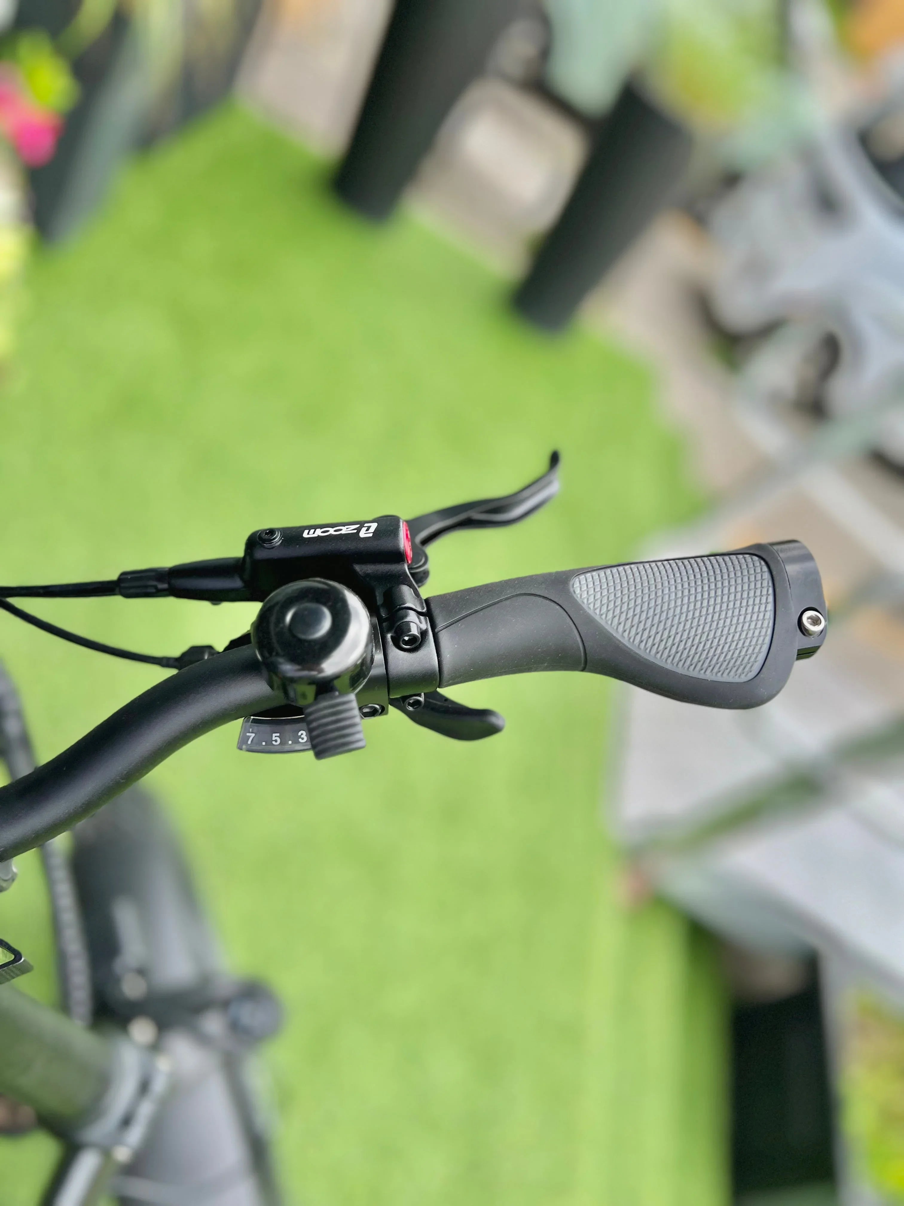 Close-up of a black bicycle handlebar with ergonomic grip and gear shifter, outdoor setting